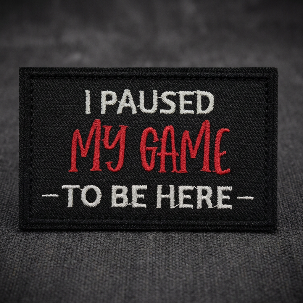 Close-up of I Paused My Game To Be Here patch on charcoal fabric